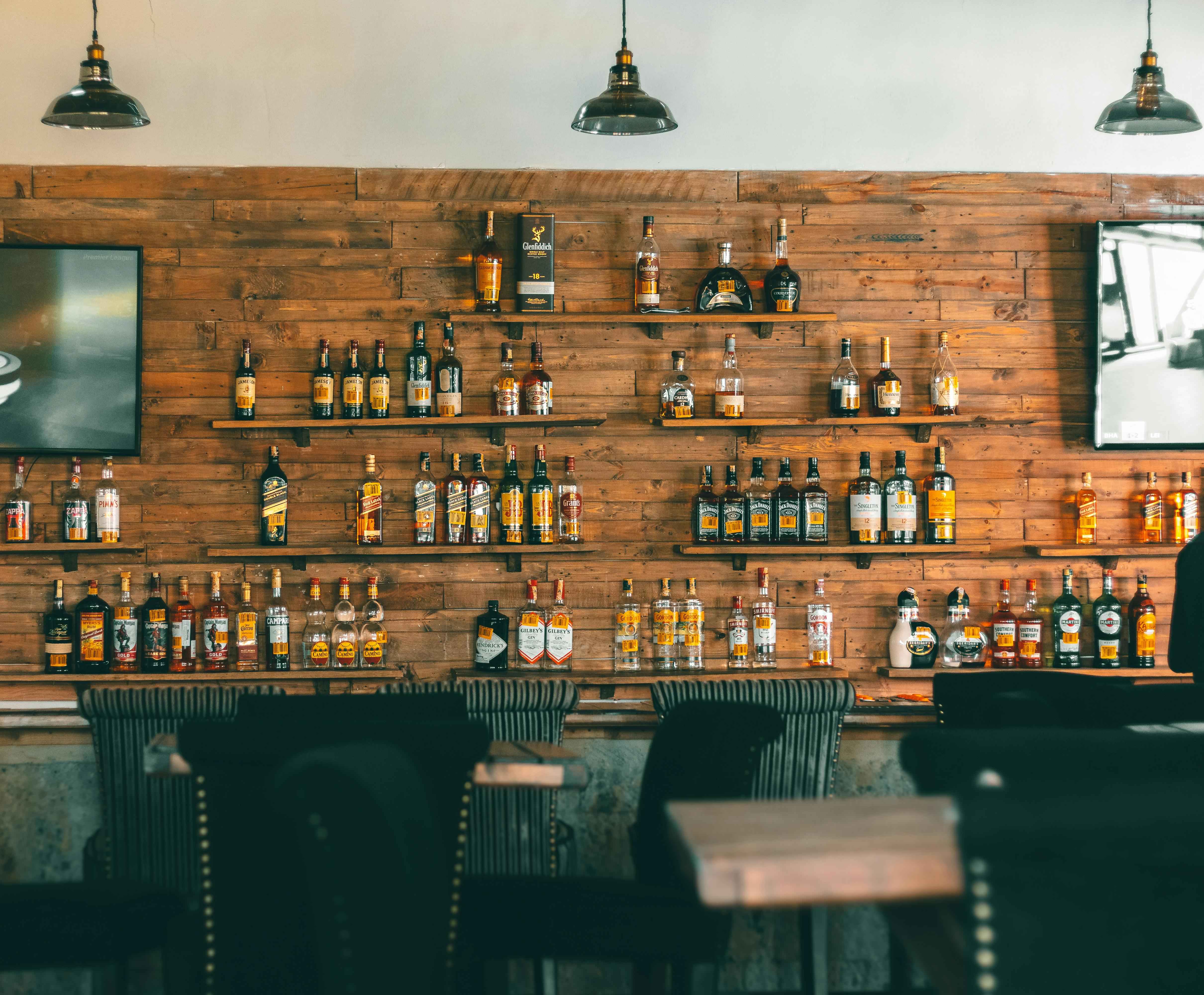 Interno di bar rustico in legno con una selezione di bottiglie di whisky dietro il bancone Interno di bar rustico in legno con una selezione di bottiglie di whisky dietro il bancone